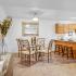 Kitchen with dining table and chairs, console table with light and cabinets.